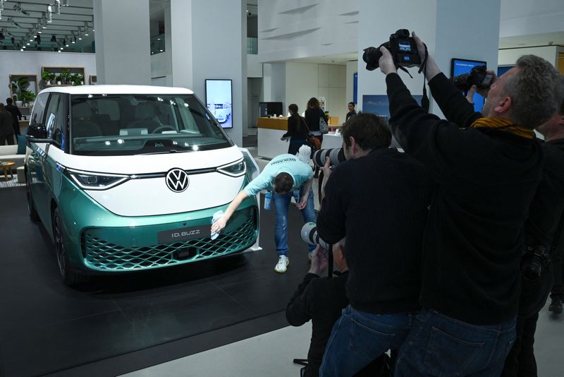 © Reuters. Photographers take pictures as a worker cleans a Volkswagen ID. Buzz EV car, on the day of the annual news conference of the Volkswagen Group at DRIVE.Volkswagen Group Forum, in Berlin, Germany March 14, 2023. REUTERS/Annegret Hilse