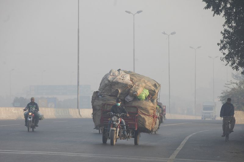 &copy; Reuters. رجل يقود دراجة ثلاثية العجلات محملة بأكياس من مواد قابلة لإعادة التدوير وسط ضباب دخاني كثيف في مدينة لاهور الباكستانية. صورة من أرشيف رويتر