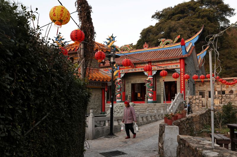 &copy; Reuters. FILE PHOTO: A woman carrying water bottles walks past a temple at a village on Nangan island, the main island of the Taiwan-controlled Matsu islands January 28, 2021. REUTERS/Ann Wang/File Photo