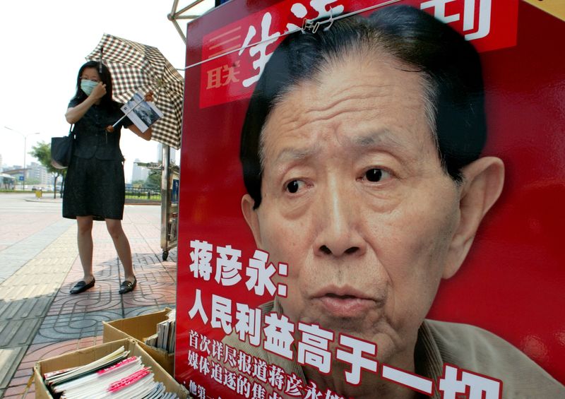 &copy; Reuters. FILE PHOTO: A CHINESE WOMAN ADJUSTS HER FACE MASK AT A NEWSPAPER STALL FEATURING A PHOTO OF DR JIANG YANYONG IN BEIJING on  5 June, 2003/Reuters photographer./