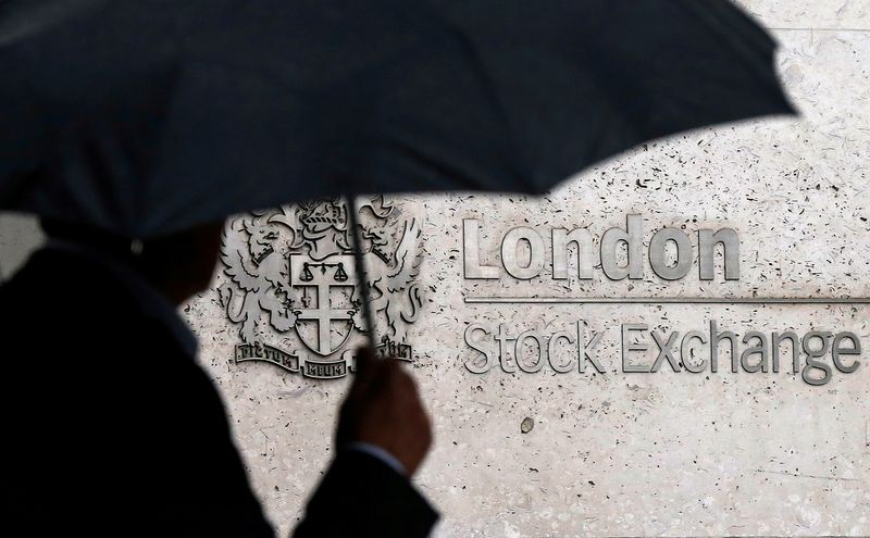 © Reuters. FILE PHOTO: A man shelters under an umbrella as he walks past the London Stock Exchange in London, Britain, August 24, 2015. REUTERS/Suzanne Plunkett