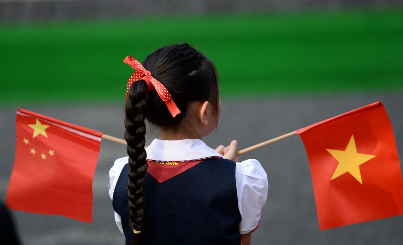 &copy; Reuters. FILE PHOTO: A Vietnamese pupil holds Chinese and Vietnamese flags before a welcoming ceremony for China's President Xi Jinping at the Presidential Palace in Hanoi, Vietnam, Nov. 12, 2017. REUTERS/Hoang Dinh Nam/Pool