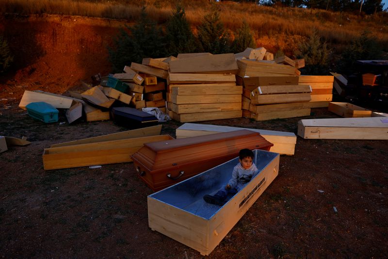 © Reuters. Mehmet Dogru, 6, plays inside an open coffin at Cankaya cemetery, where his family moved to in the aftermath of a deadly earthquake in Iskenderun, Turkey, March 8, 2023. Last month's devastating earthquakes killed more than 54,000 people in Turkey and Syria and left millions homeless. Mehmet's family lives in a tent behind the morgue, next to a bus that shelters the family of his uncle, who works at the cemetery as an undertaker.           REUTERS/Susana Vera     