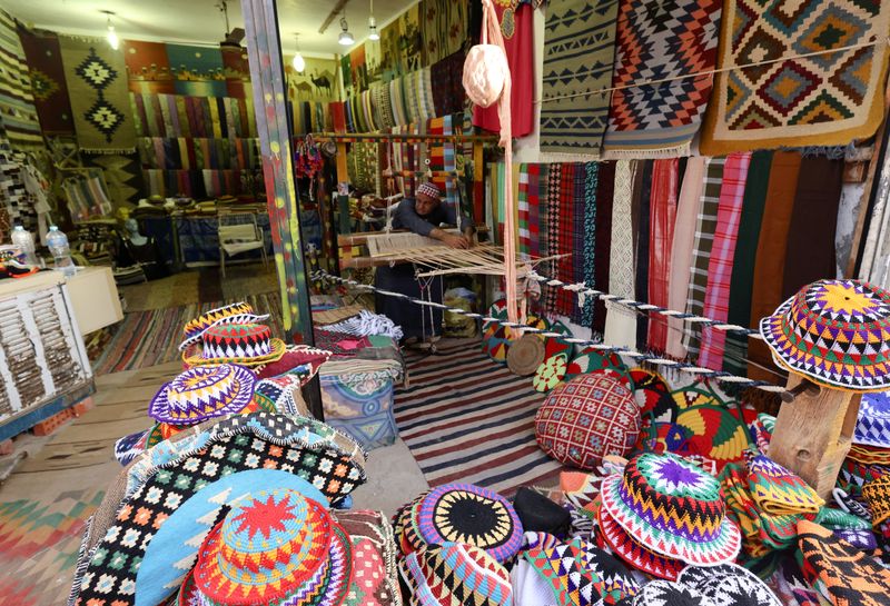 © Reuters. Yousef Naaiem, 65, weaves a carpet on a handmade loom in his shop with traditional souvenirs, at the Gharb Soheil village, on the west bank of the Nile river, in the southern Egyptian city of Aswan, Egypt March 8, 2023. REUTERS/Amr Abdallah Dalsh
