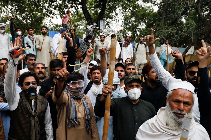 © Reuters. Supporters of former Pakistani Prime Minister Imran Khan carry bamboo sticks and slingshots, as they gather and chant slogans, at the entrance of Khan's house, in Lahore, Pakistan March 17, 2023. REUTERS/Akhtar Soomro