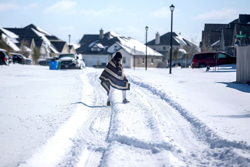 &copy; Reuters. FILE PHOTO: A man walks to his friend's home in a neighborhood without electricity as snow covers the BlackHawk neighborhood in Pflugerville, Texas, U.S. February 15, 2021.  Bronte Wittpenn/Austin American-Statesman/USA Today Network via REUTERS