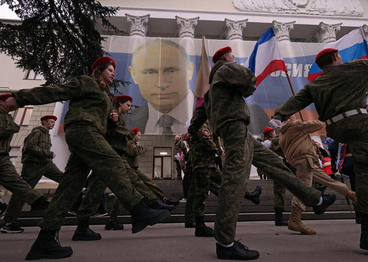 &copy; Reuters. Decenas de personas participan en un desfile junto a un cartel del presidente ruso, Vladimir Putin, con motivo del noveno aniversario de la anexión rusa de Crimea, en Yalta, Crimea. 17 marzo 2023. REUTERS/Alexey Pavlishak