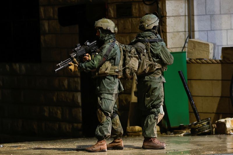 © Reuters. Israeli troops stand guard at the scene of a shooting, in Huwara, in the Israeli-occupied West Bank, March 19, 2023. REUTERS/Mohamad Torokman