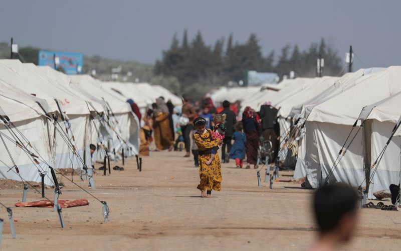 &copy; Reuters. FILE PHOTO: A girl walks as she carries a child past tents erected for the internally displaced following an earthquake, on a land that was previously a driving school, in the rebel-held town of Jandaris, Syria March 4, 2023. REUTERS/Khalil Ashawi