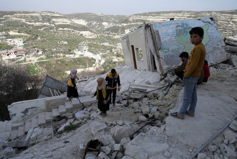 &copy; Reuters. FILE PHOTO: Salam Mahmoud, a volunteer at the Syria Civil Defence (White Helmets), walks with other volunteers on the rubble of a building, that was damaged by last month's devastating earthquake, in rebel-held al-Maland village, in Idlib province, Syria 