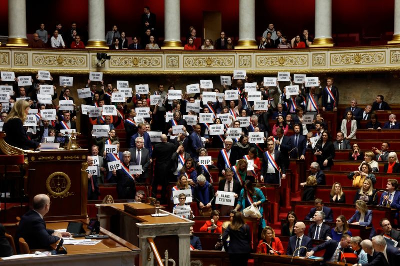 &copy; Reuters. Des députés de gauche brandissent des pancartes après le résultat du vote sur la première motion de censure contre le gouvernement français, déposée par le groupe centriste Liot, après l'utilisation par le gouvernement français de l'article 49.3