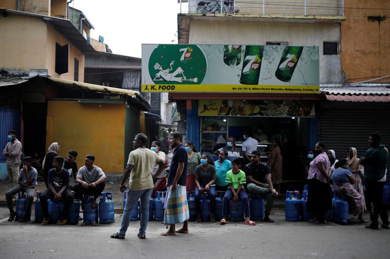 &copy; Reuters. FILE PHOTO: People sit on their empty cylinders as they wait in a queue to buy domestic gas at a distribution centre, amid the country's economic crisis, in Colombo, Sri Lanka, May 20, 2022. REUTERS/Adnan Abidi