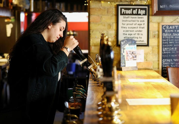 © Reuters. A barmaid pours a pint at a pub in Cambridge, Britain, January 24, 2023. REUTERS/Matthew Childs