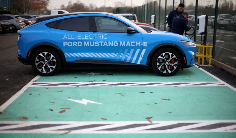 &copy; Reuters. FILE PHOTO: Workers plug in an electric Ford Mustang Mach-e electric vehicle during a press event at the Ford Halewood transmissions plant in Liverpool, Britain, December 1, 2022. REUTERS/Phil Noble/File Photo