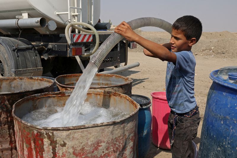 &copy; Reuters. Haider Jalil, de 10 anos, enche tanque de água de caminhão fora da casa de sua família na vila de Al-Bouzayyat, às margens de canal que secou, ​​em Diwaniya, Iraque
20/10/2022
REUTERS/Alaa Al-Marjani