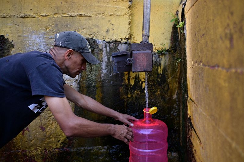 &copy; Reuters. FILE PHOTO: A man fills plastic container with water from a natural creek, in Caracas, Venezuela March 22, 2023. REUTERS/Gaby Oraa