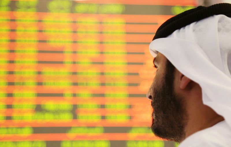 &copy; Reuters. متداول ينظر إلى شاشات تعرض حركة الأسهم في سوق دبي المالية. صورة من أرشيف رويترز 