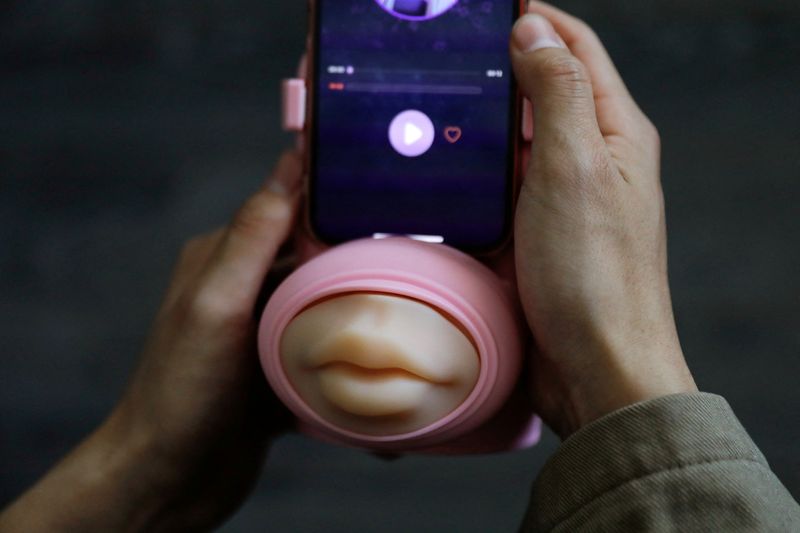 &copy; Reuters. Jing Zhiyuan uses a remote kissing device "Long Lost Touch", as he demonstrates how to use it during an interview with Reuters, at his home in Beijing, China March 12, 2023. REUTERS/Tingshu Wang