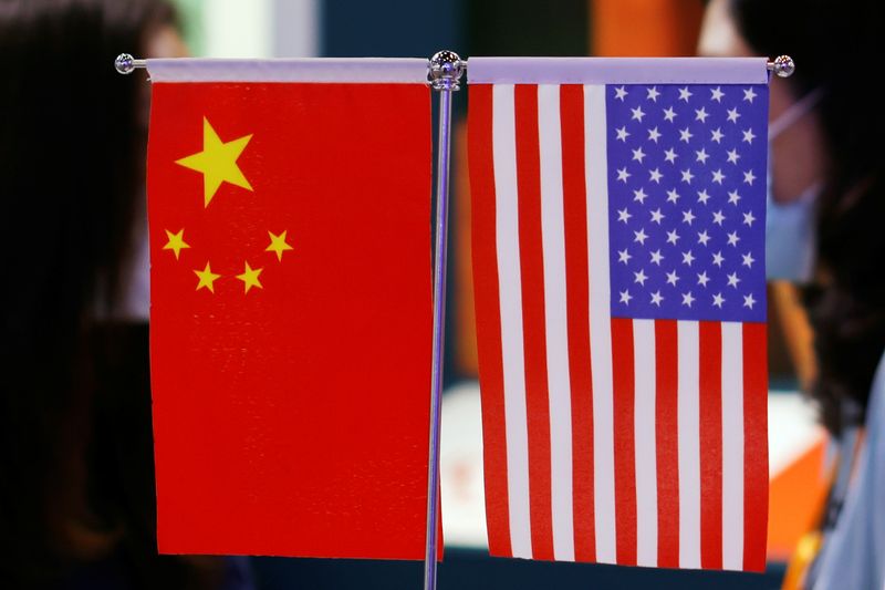 © Reuters. Staff members chat behind Chinese and U.S. flags displayed at the 2021 China International Fair for Trade in Services (CIFTIS) in Beijing, China September 4, 2021. REUTERS/Florence Lo