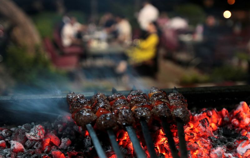 © Reuters. FILE PHOTO: Minced meat kebab is seen being cooked on a barbecue as restaurant customers have dinner in Islamabad, Pakistan July 24, 2017.  REUTERS/Caren Firouz