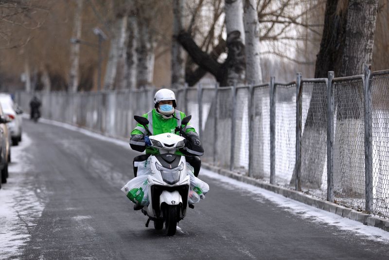 &copy; Reuters. FILE PHOTO: A Meituan delivery worker rides a scooter carrying vegetables on a snowy day in Beijing, China January 19, 2021. REUTERS/Tingshu Wang
