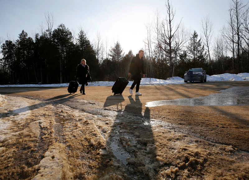 &copy; Reuters. FILE PHOTO: People walk with their luggage on Roxham Road before crossing the US-Canada border into Canada in Champlain, New York, U.S., February 14, 2018.   REUTERS/Chris Wattie/File Photo