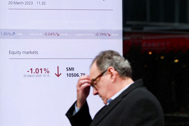 &copy; Reuters. Una persona cammina davanti a uno schermo che mostra lo Swiss market index (Smi) presso la banca svizzera Ubs a Zurigo, Svizzera, 20 marzo 2023. REUTERS/Denis Balibouse/File Photo