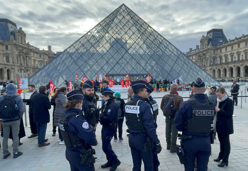 &copy; Reuters. La policía francesa observa mientras los manifestantes que sostienen banderas del sindicato francés CGT frente a la Pirámide de cristal bloquean la entrada del museo del Louvre para protestar contra la reforma de las pensiones del gobierno francés, en