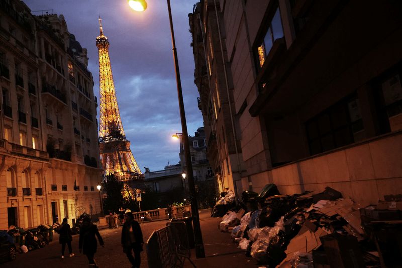 &copy; Reuters. سكان وسائحون يسيرون قرب أكوام من القمامة في شارع قرب برج إيفل في باريس بسبب عدم جمع القمامة بسبب إضراب جامعيها احتجاجا على خطة الحكومة الفرن