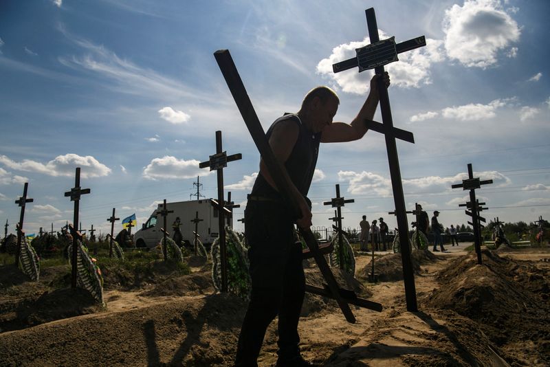 &copy; Reuters. FILE PHOTO: A volunteer places a cross onto a grave of one of fifteen unidentified people killed by Russian troops, amid Russia's attack on Ukraine continues, during a burial ceremony in the town of Bucha, in Kyiv region, Ukraine September 2, 2022.  REUTE