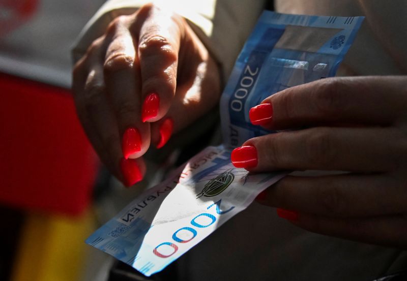 &copy; Reuters. FILE PHOTO: A customer holds a Russian 2000-rouble banknote in a grocery store in Omsk, Russia March 31, 2021. REUTERS/Alexey Malgavko