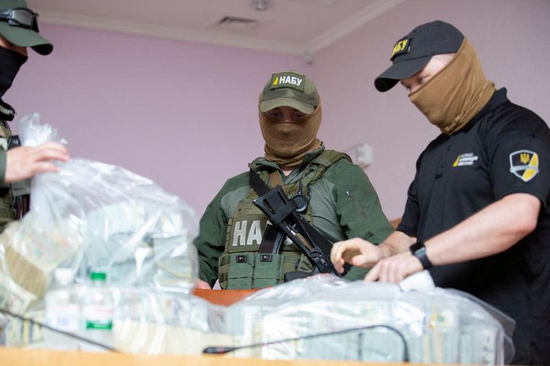 &copy; Reuters. FILE PHOTO: Officers stand next to plastic bags filled with U.S. Dollar banknotes seized by the National Anti-Corruption Bureau of Ukraine, before a news briefing at the anti-corruption prosecutor's office in Kiev, Ukraine June 13, 2020. Press Service of 