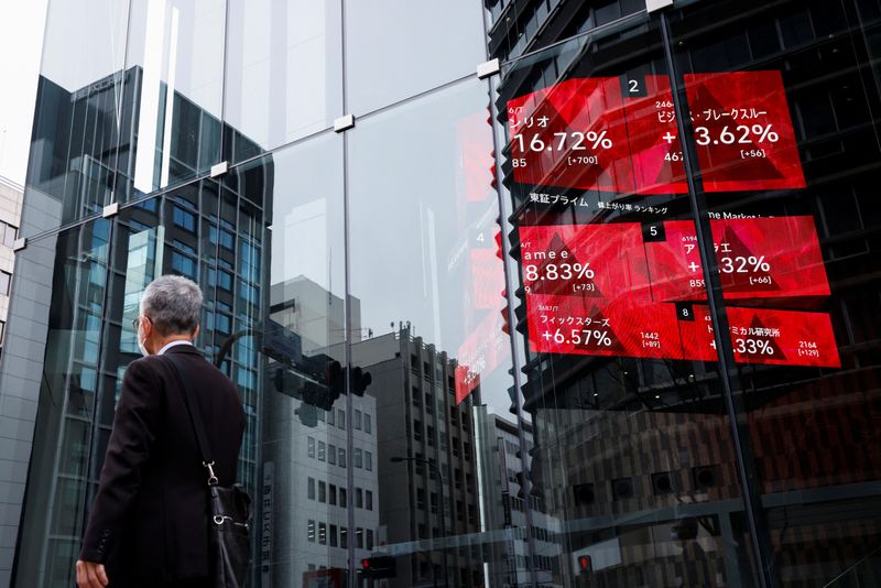 &copy; Reuters. FILE PHOTO: A man walks past an electronic board showing stock visualizations outside a brokerage, in Tokyo, Japan, March 17, 2023. REUTERS/Androniki Christodoulou