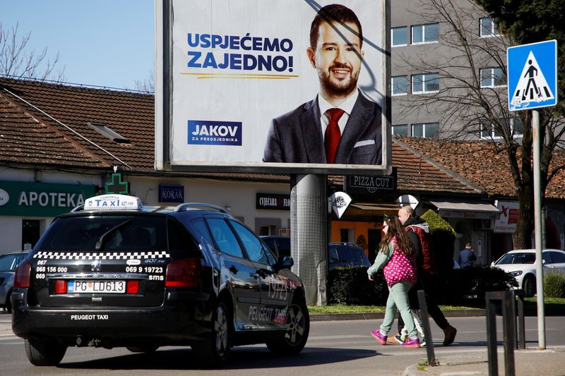 &copy; Reuters. A taxi waits for pedestrians at a street crossing under a pre-election billboard of candidate Jakov Milatovic in Podgorica, Montenegro, March 30, 2023. REUTERS/Stevo Vasiljevic