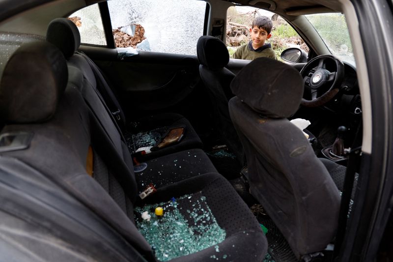 © Reuters. طفل ينظر إلى سيارة عائلة عمر خليفة التي تعرضت للهجوم من قبل مستوطنين إسرائيليين في حوارة بالأرضي الفلسطينية المحتلة يوم 7 مارس آذار 2023. تصوير: رنين صوافطة - رويترز 