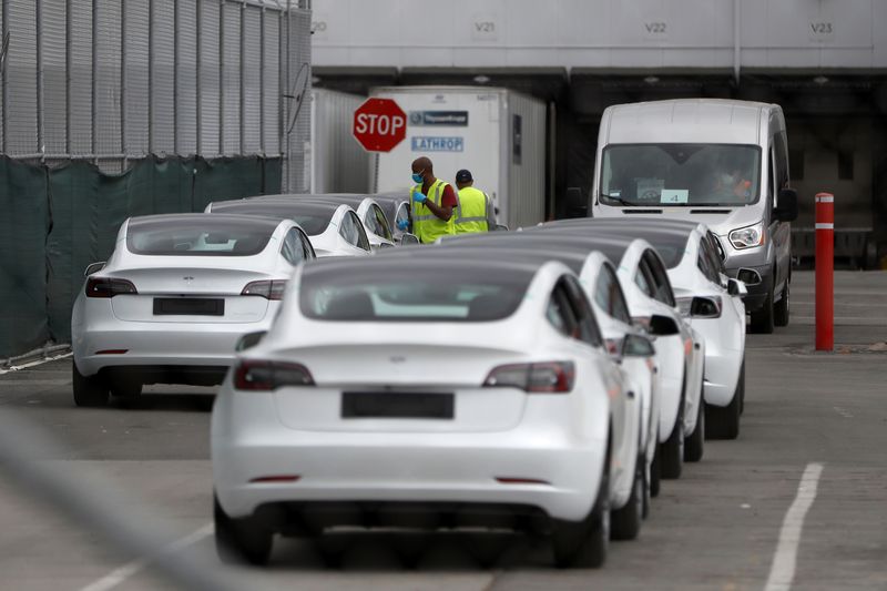 &copy; Reuters. FILE PHOTO: Workers walk among a row of Tesla Model 3 electric vehicles at Tesla's primary vehicle factory after CEO Elon Musk announced he was defying local officials' coronavirus disease (COVID-19) restrictions by reopening the plant in Fremont, Califor