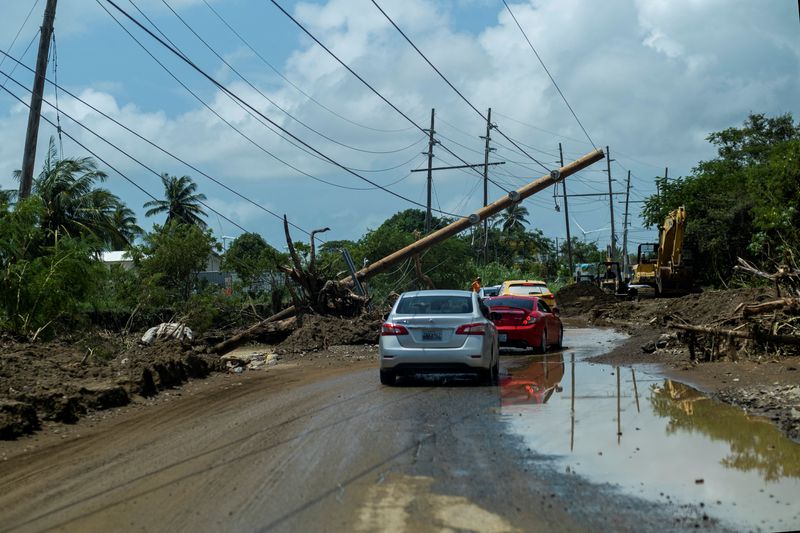 &copy; Reuters. FILE PHOTO: Cars drive under a downed power pole in the aftermath of Hurricane Fiona in Santa Isabel, Puerto Rico September 21, 2022. REUTERS/Ricardo Arduengo