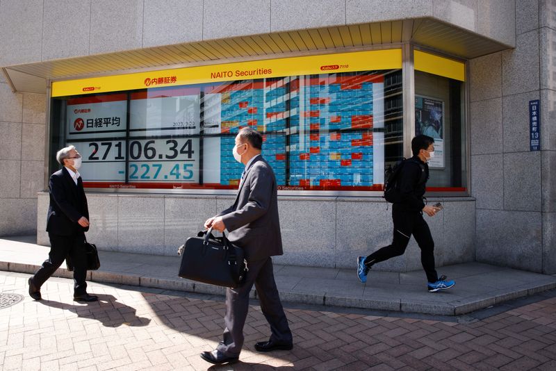 &copy; Reuters. FILE PHOTO: Passersby walk past an electronic board showing Japan's Nikkei average and stock quotations outside a brokerage, in Tokyo, Japan, March 20, 2023. REUTERS/Androniki Christodoulou