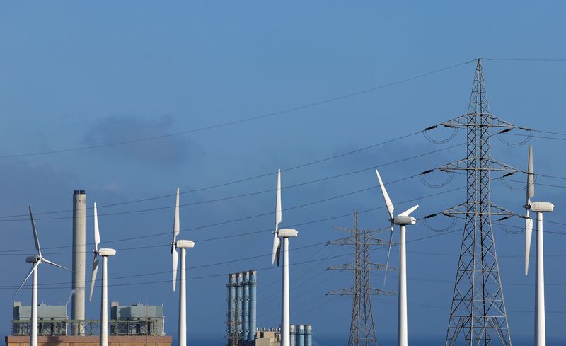 &copy; Reuters. Líneas de alta tensión y un poste eléctrico junto a un grupo de aerogeneradores en el Barranco de Tirajana, en la isla de Gran Canaria, España. 11 de mayo de 2022. REUTERS/Borja Suárez