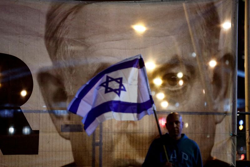 &copy; Reuters. رجل يحمل العلم الإسرائيلي وهو يقف أمام صورة كبيرة لرئيس الوزراء الإسرائيلي بنيامين نتنياهو خلال مظاهرة ضد الإصلاحات القضائية المقترحة من ق