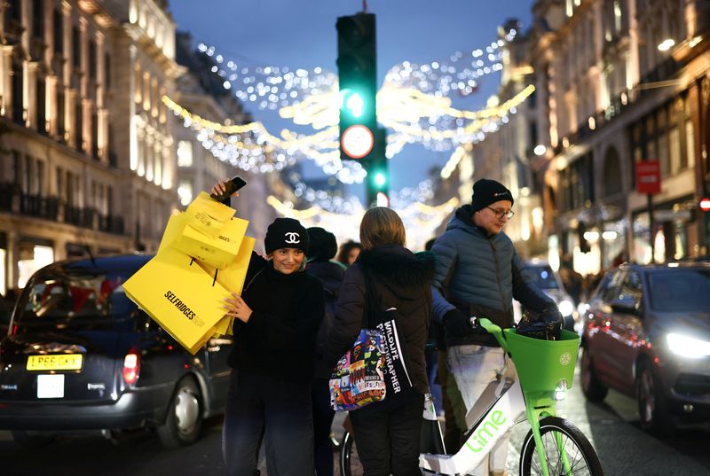 &copy; Reuters. FILE PHOTO: People carry shopping bags as they walk past Christmas themed shop displays on Regent Street in London, December 4, 2022. REUTERS/Henry Nicholls