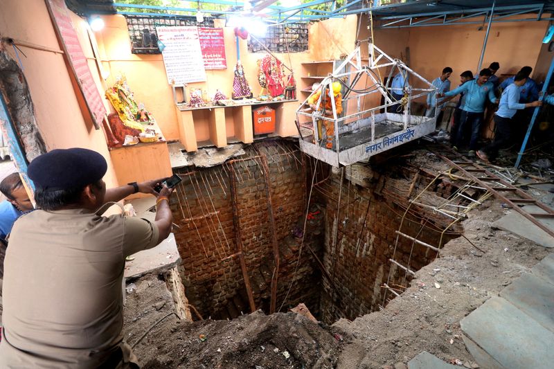 &copy; Reuters. ضابط شرطة يلتقط صورا بهاتفه المحمول أثناء عملية إنقاذ بعد انهيار سقف داخل معبد في مدينة إندور بولاية ماديا براديش الهندية يوم 31 مارس آذار 2023