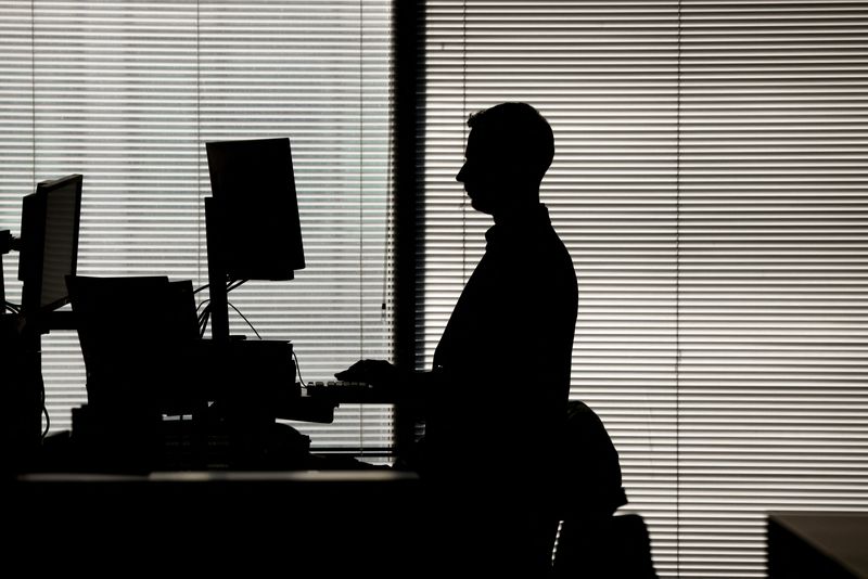 © Reuters. FILE PHOTO: A man works at a computer on a standing desk in an office in the financial district of Canary Wharf in London, Britain, February 8, 2023. REUTERS/Kevin Coombs