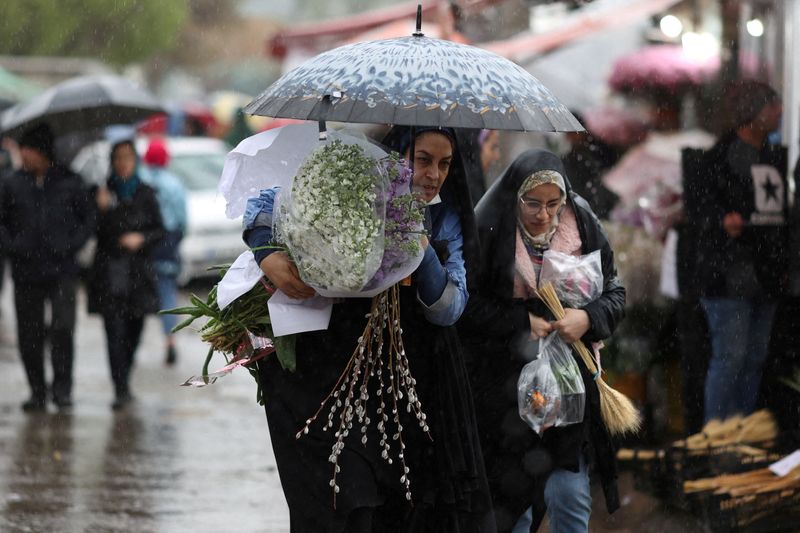 &copy; Reuters. نساء إيرانيات يمشين في المطر بأحد أسواق الورود في طهران يوم 16 مارس آذار 2023. صورة لرويترز من وكالة أنباء غرب آسيا 