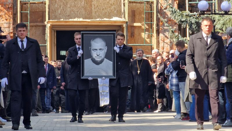 &copy; Reuters. شخصان يحملان صورة للمدون الروسي المؤيد للحرب فلادلين تاتارسكي خلال جنازته بموسكو يوم السبت عقب مقتله في انفجار بمقهى . تصوير : رويترز .  
