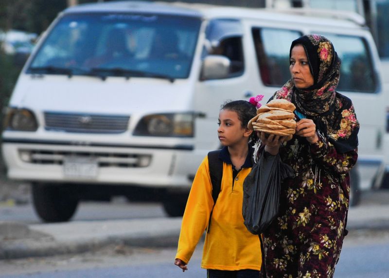 &copy; Reuters. FILE PHOTO: A woman carrying bread walks her daughter to school in the Giza suburb of Awsim, Egypt October 10, 2021. REUTERS/Shokry Hussien