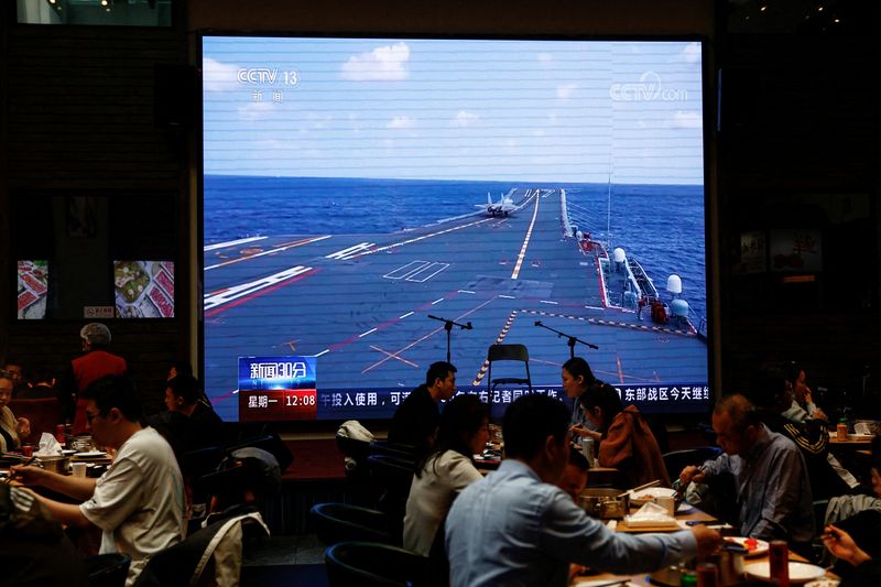 &copy; Reuters. Customers dine near a giant screen broadcasting news footage of an aircraft taking off from China's Shandong aircraft carrier while taking part in a combat readiness patrol and "Joint Sword" exercises around Taiwan conducted by the Eastern Theatre Command