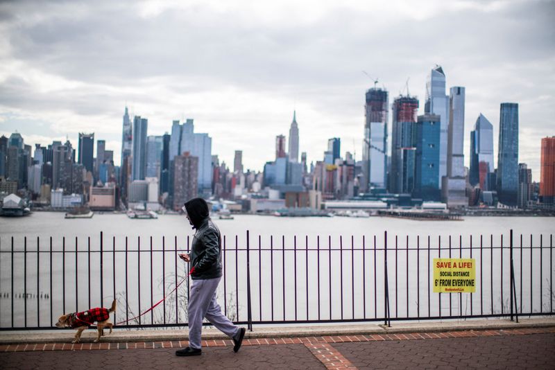 &copy; Reuters. FILE PHOTO: A man walks his dog without wearing a face mask during the coronavirus disease (COVID-19) pandemic, while the Empire State Building and New York skyline are seen from Weehawken, in New Jersey, U.S., April 2, 2021. REUTERS/Eduardo Munoz
