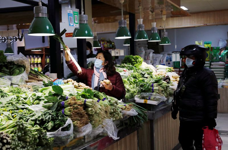 &copy; Reuters. FILE PHOTO: People wearing face masks shop at a market, following new cases of the coronavirus disease (COVID-19) in the country, in Beijing, China January 11, 2021. REUTERS/Tingshu Wang