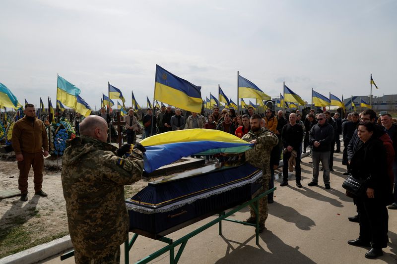 &copy; Reuters. Ukrainian service members hold a national flag over a coffin with the body of their brother-in-arms Kostiantyn Starovytskyi, conductor, musician and serviceman, who was recently killed in a fight against Russian troops in Donetsk region, amid Russia's att